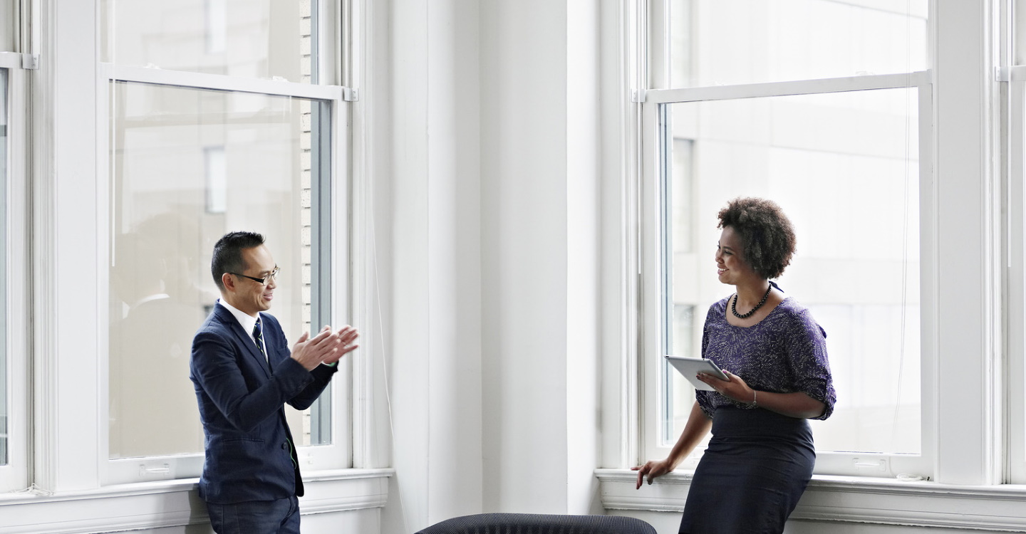 Businesswoman holding tablet and discussing project with businessman in office
